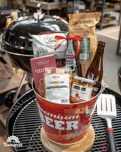 Panier garni cadeau dans un pot rouge contenant tapenade, chips et boissons.